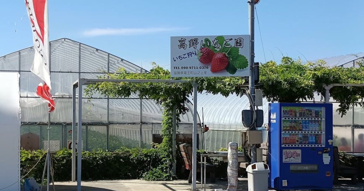 Entrance to a Japanese strawberry farm featuring a greenhouse and vending machine.