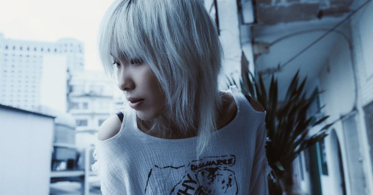 Stylish portrait of a person with platinum hair in an urban setting, captured in cool tones.