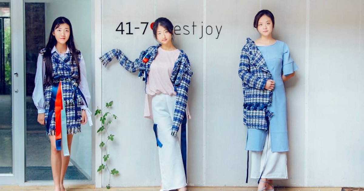 Three women posing indoors in trendy blue and white fashion attire.