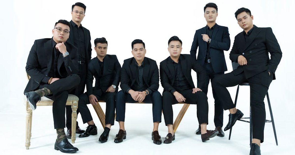 A stylish group of men in suits posing elegantly against a white backdrop in a studio setting.