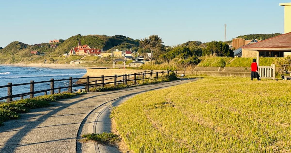 Serene coastal pathway with ocean view and distant hillside homes during summer day.