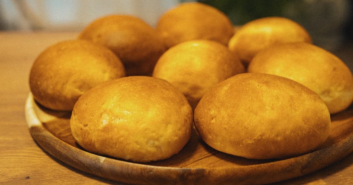 Delicious golden brown bread rolls displayed on a wooden table, perfect for culinary presentations.