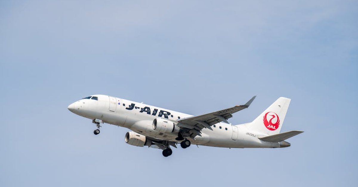 A J-Air passenger plane flies high against a clear blue sky, capturing aviation travel moments.