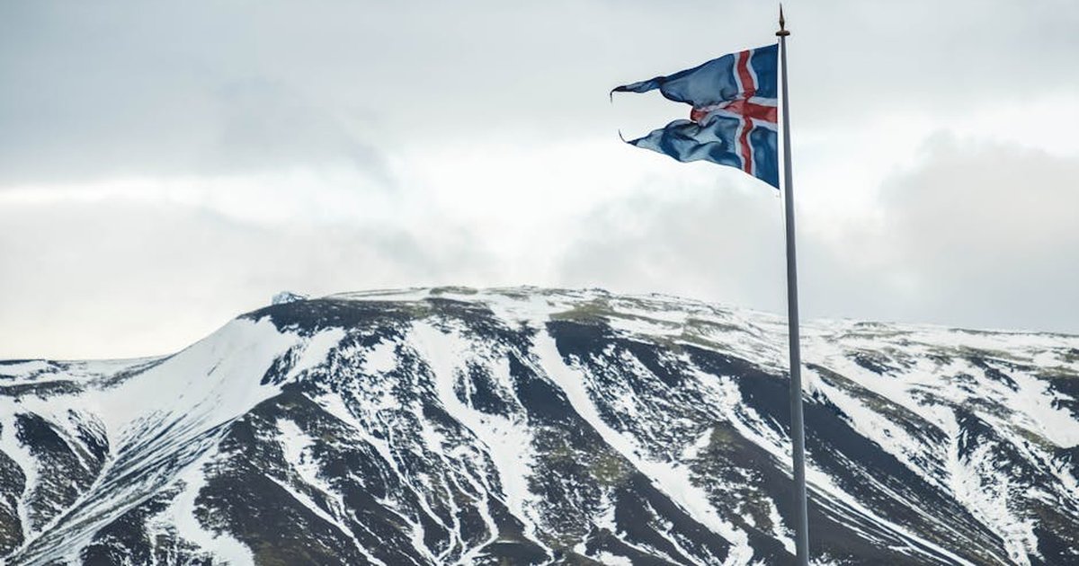 Icelandic flag flying against a backdrop of snow-covered mountains, capturing Iceland's natural beauty.