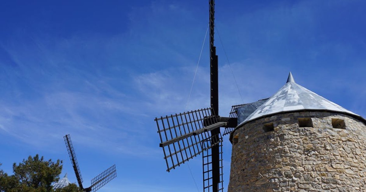 Two traditional stone windmills under a clear blue sky, capturing historical charm and rustic architecture.