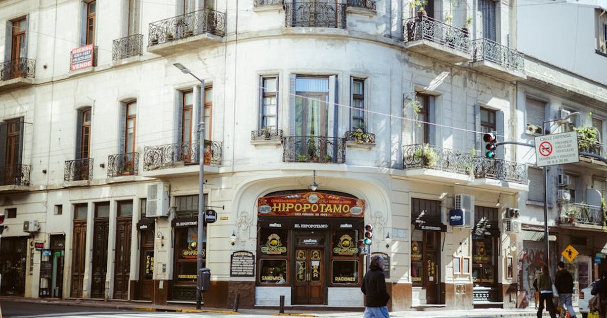 A bustling street corner in Buenos Aires featuring the iconic Hipopotamo Cafe and pedestrians crossing.