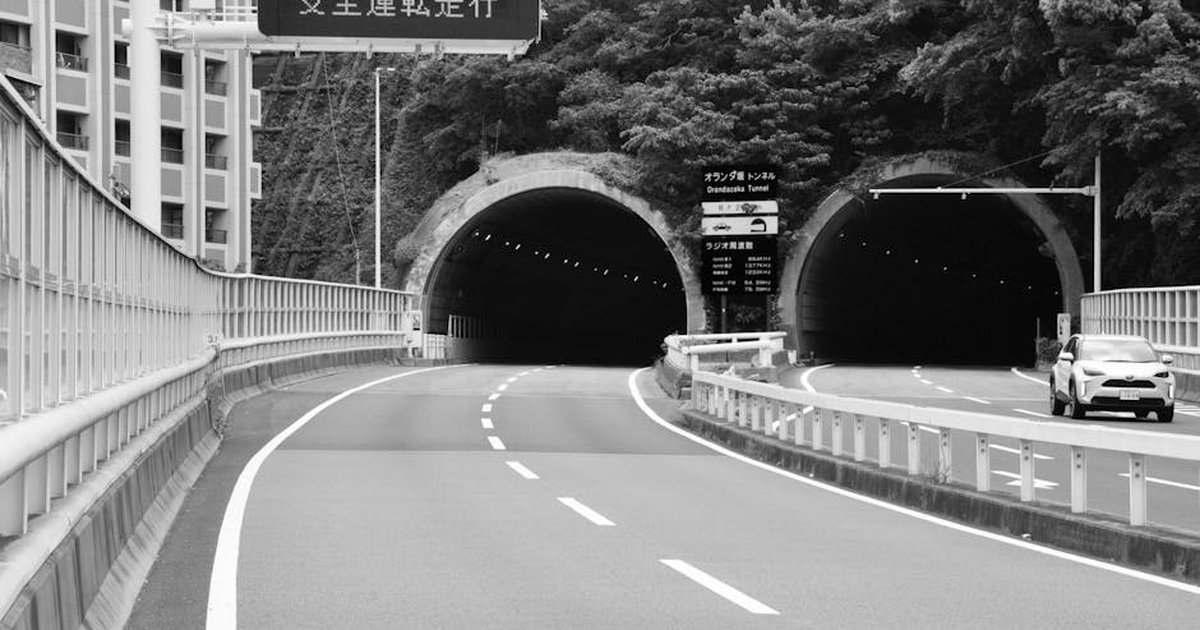 Black and white image of Onaribashi Tunnel with deserted road and modern SUV.