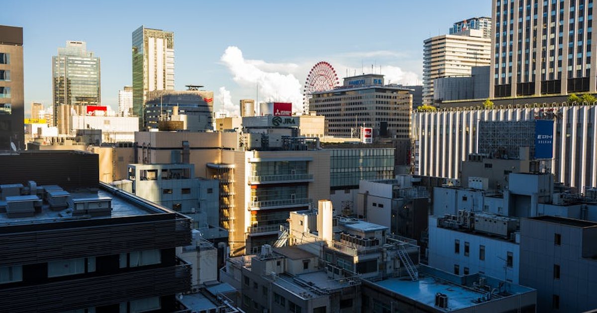 View of Osaka city's urban skyline featuring a Ferris wheel under clear daylight.