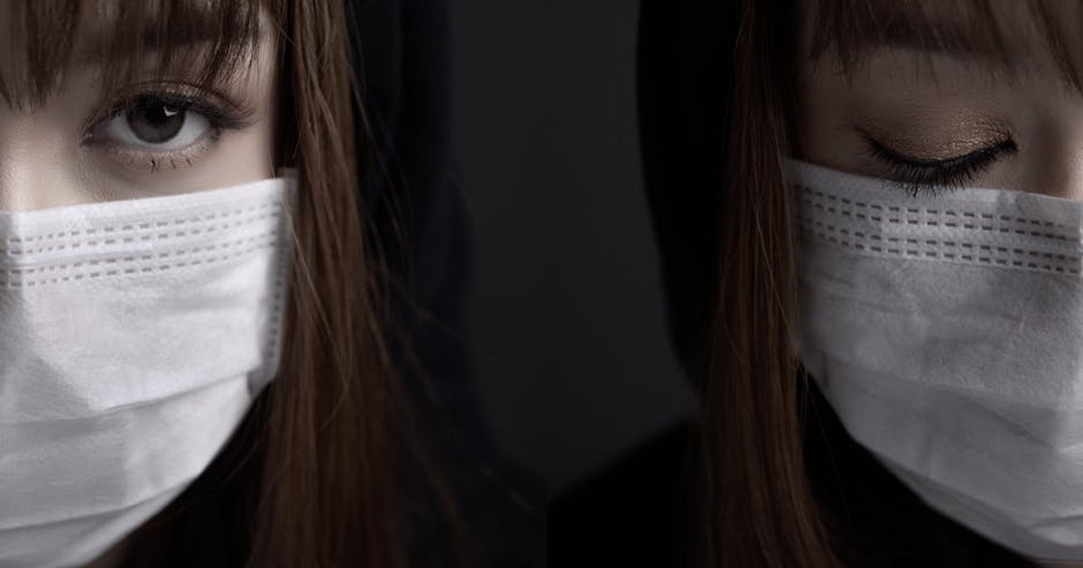 Close-up of a woman wearing a face mask against a dark background, evoking a sense of mystery.