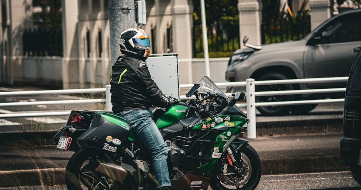A rider on a Kawasaki Ninja H2 sports bike on a city street, embodying urban life.