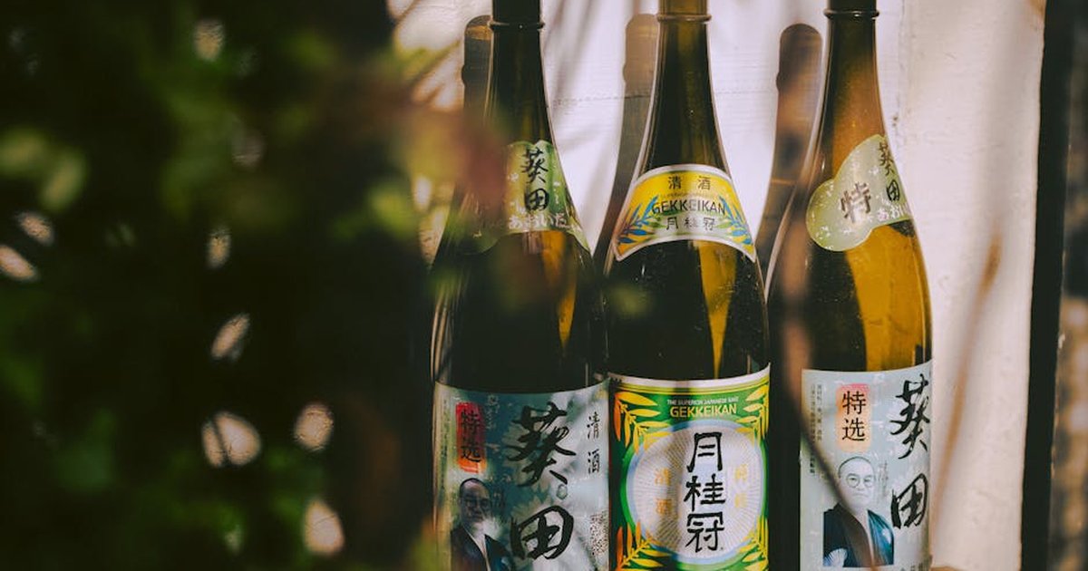 Three traditional Japanese sake bottles with distinctive labels in a natural setting.