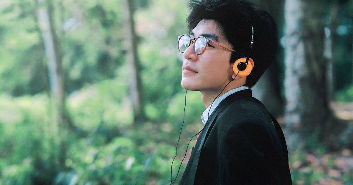 Man listening to music outdoors, enjoying a peaceful moment in lush greenery.