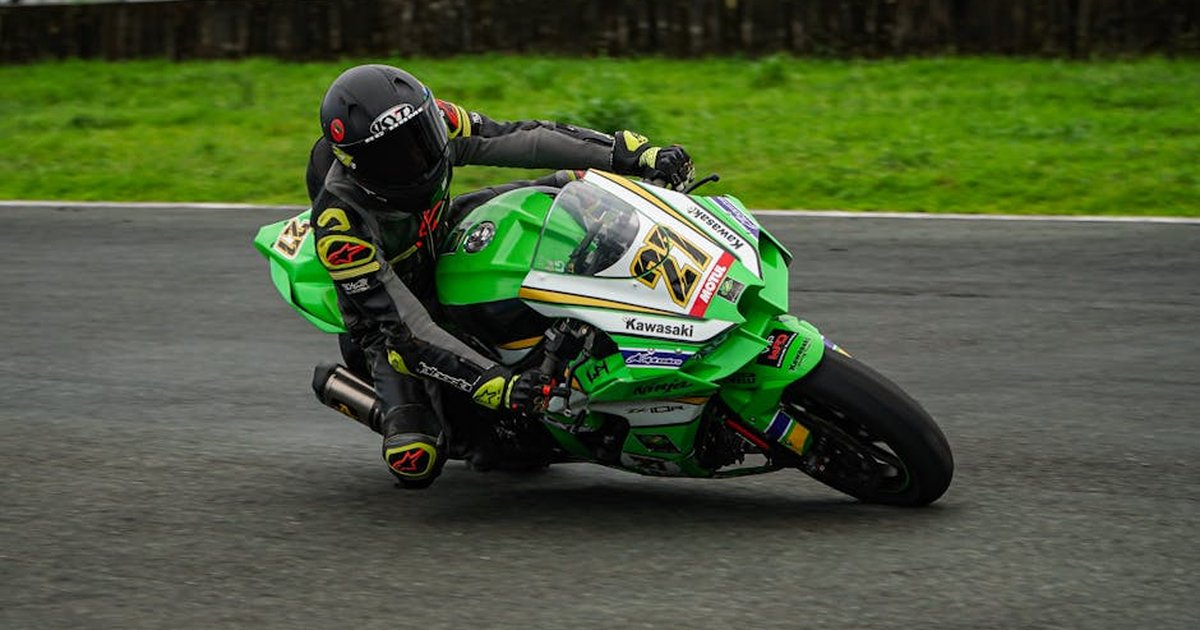 Motorcyclist racing at high speed on a track, showcasing agility and precision on a green Kawasaki bike.