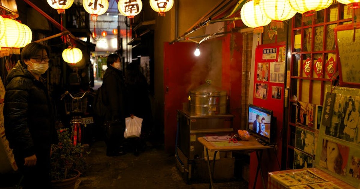 Explore a bustling Yokohama alley adorned with paper lanterns and street vendors. Captured at night.