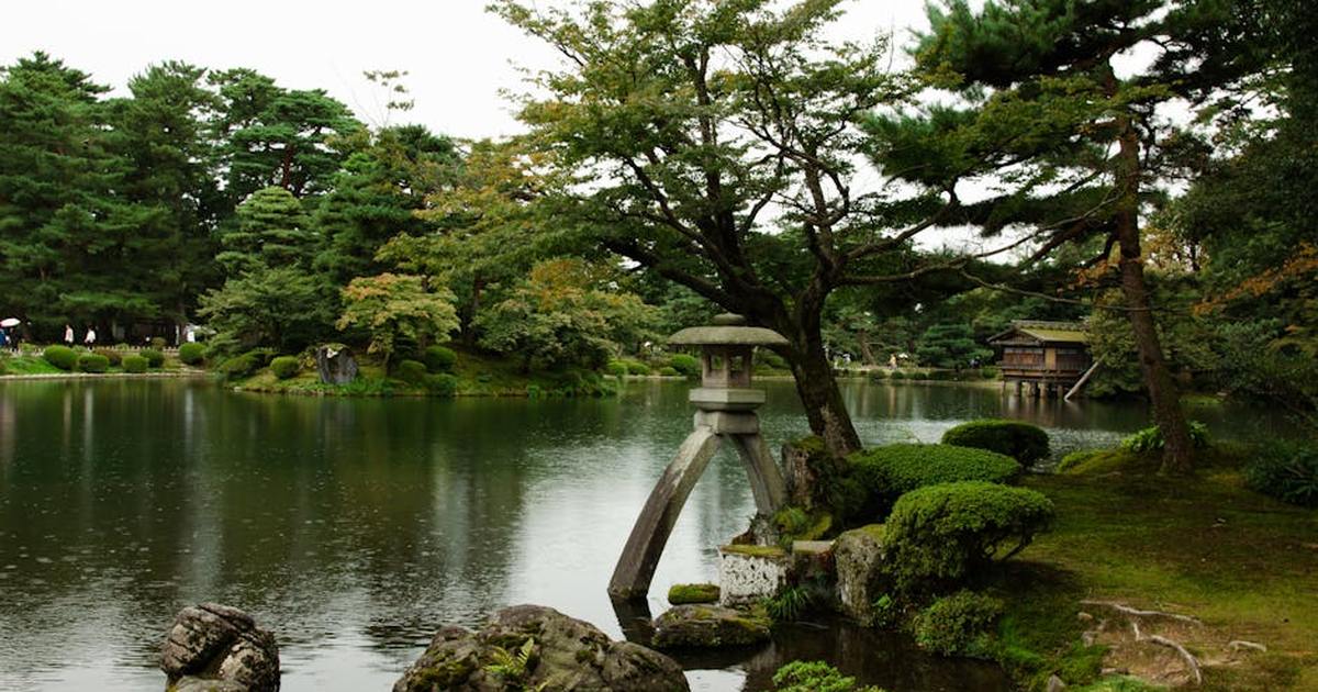 Peaceful Japanese garden with lake, stone lantern, and lush greenery. Perfect for zen relaxation.