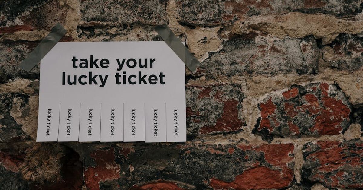 Close-up of a 'Take Your Lucky Ticket' sign taped to a rustic brick wall.
