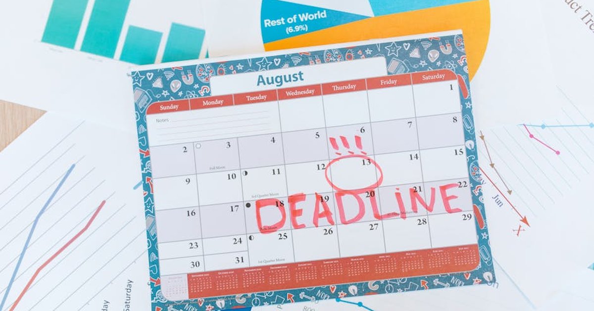 Vibrant August calendar on a desk with deadline marked in red, surrounded by graphs and charts.