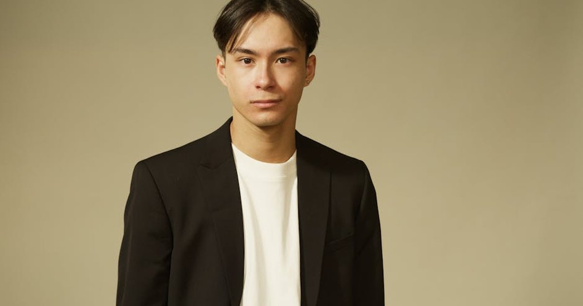 Studio portrait of a man in a black suit jacket on a neutral background.