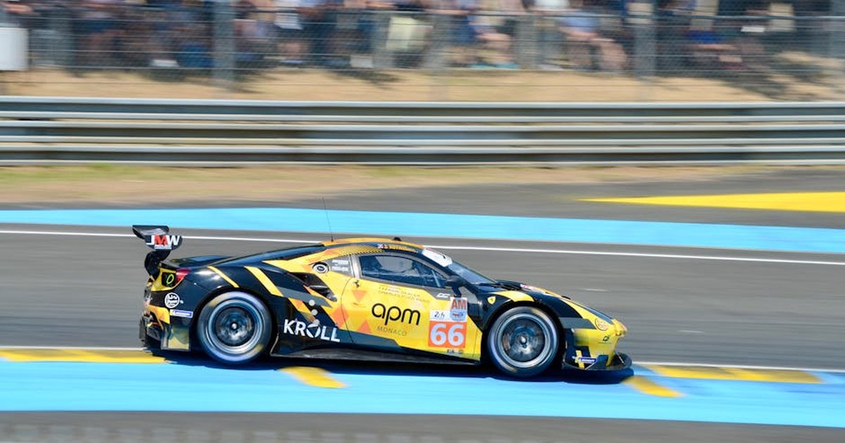 Dynamic shot of a race car speeding at Le Mans, France, showcasing vibrant colors and motion.