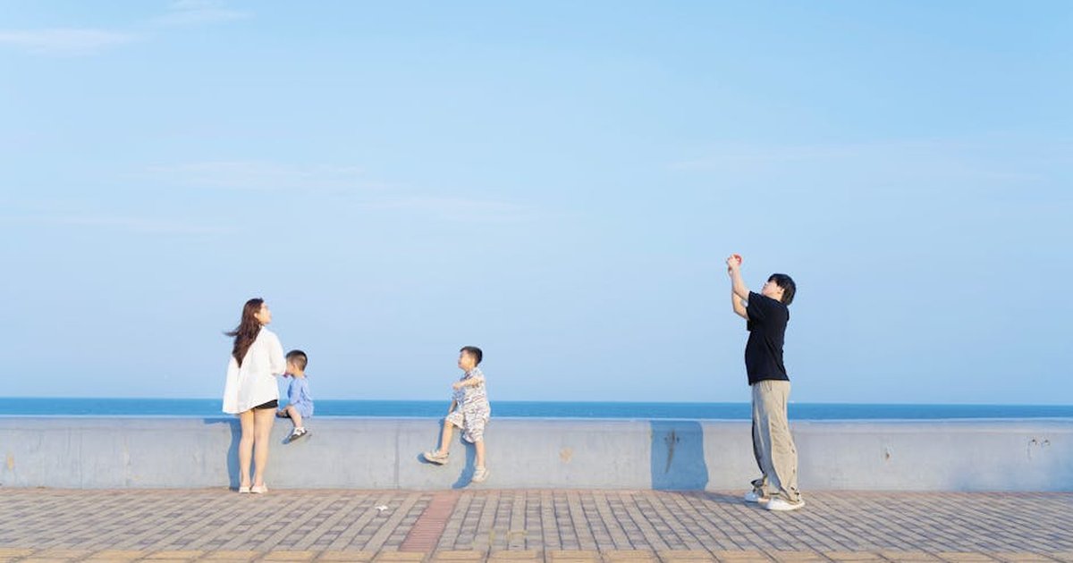 A family enjoying a sunny day by the seaside with a clear blue sky in the background.