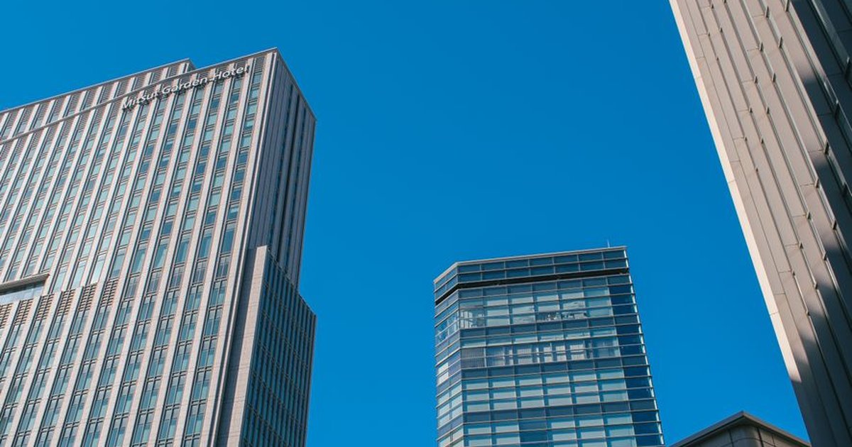 Dynamic view of modern skyscrapers rising against a clear blue sky, showcasing urban architecture.