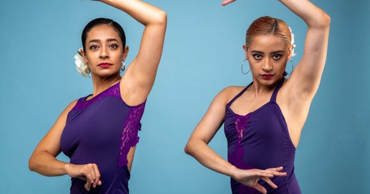 Two female dancers in purple flamenco dresses posing against a blue background.