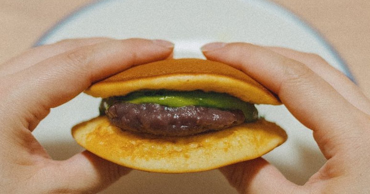 Hands holding a Japanese dorayaki filled with matcha and red bean, typical of Tokyo's culinary delights.