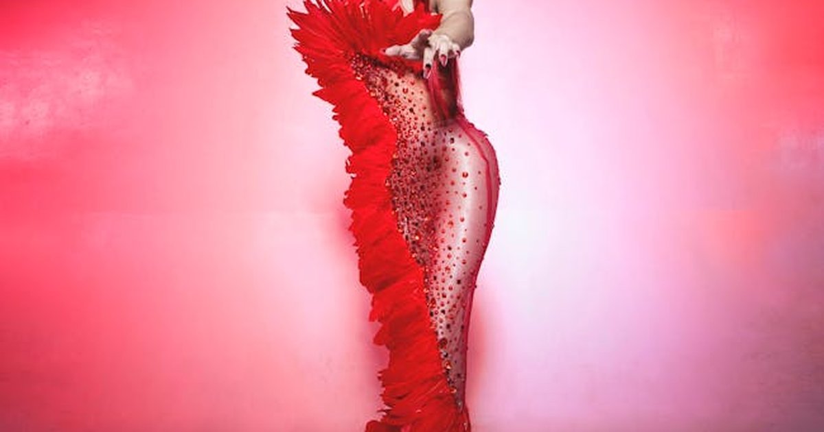 Full-body portrait of a woman in a stunning red costume with feathers, shot in studio.