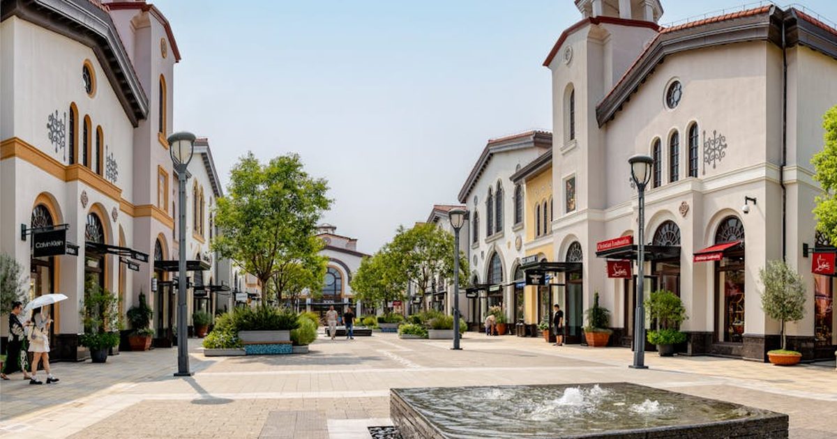 Elegant shopping arcade in Noventa di Piave, Italy bustling with tourists under a sunny sky.