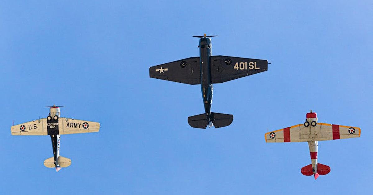 Three vintage military planes flying in formation against a clear blue sky.