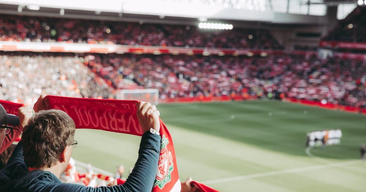 Passionate soccer supporters with scarves in Anfield Stadium, capturing the thrill of the game.
