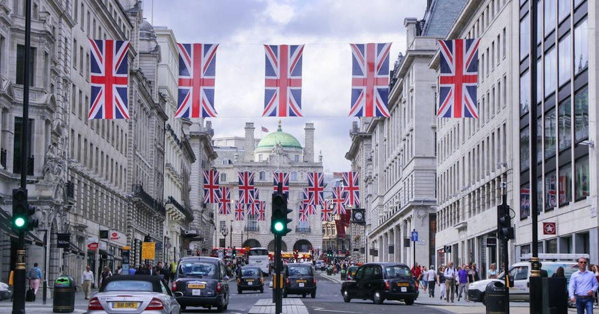 Busy London street adorned with Union Jack flags, showcasing classic architecture and bustling city life.