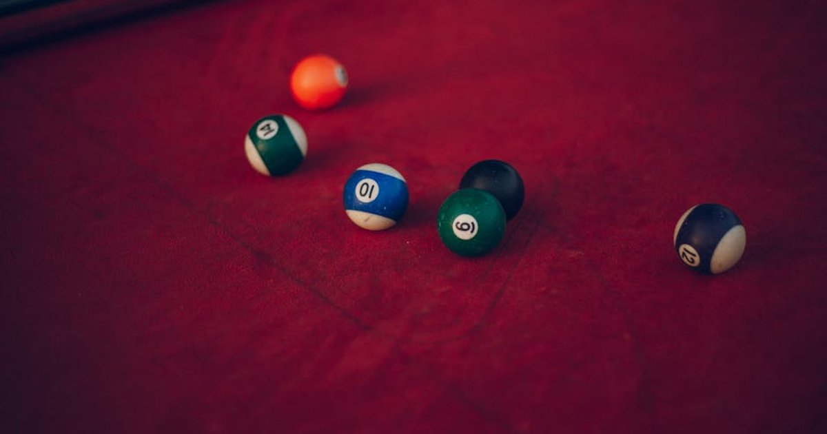 Vibrant billiard balls scattered across a red pool table, ready for a new game.