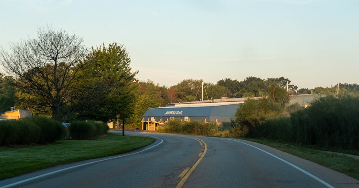 Serene evening view of a winding road leading to a building with natural surroundings in Holland, Michigan.