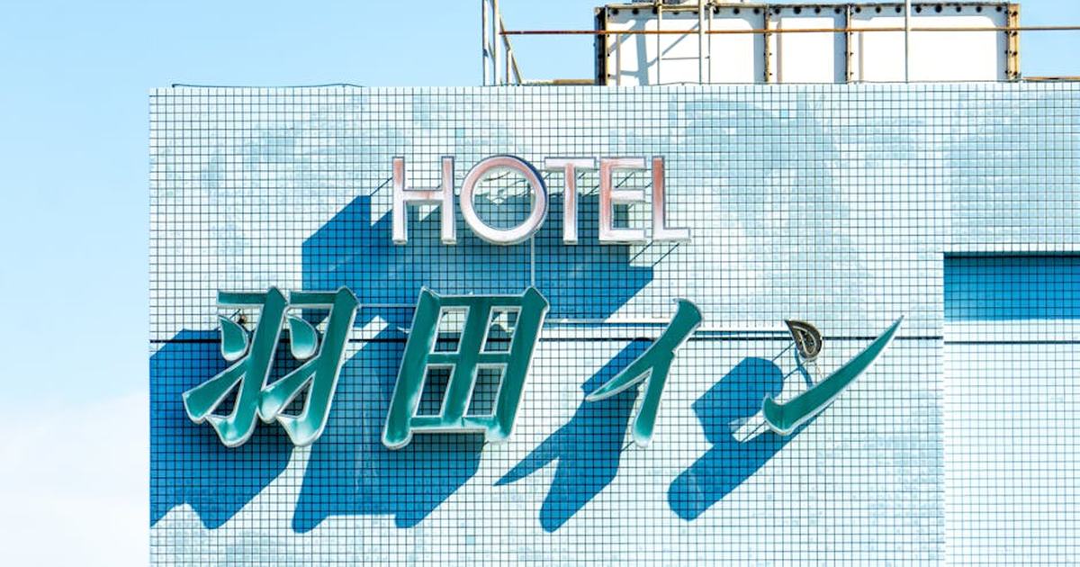 Brightly lit hotel sign with blue tiles under a clear sky, showcasing modern architecture.