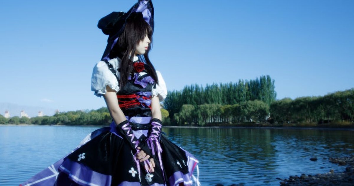 Cosplay enthusiast by serene lake in Zhangye, China, under bright blue sky.