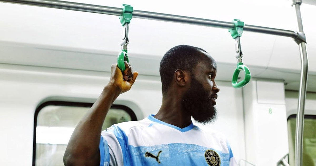 African man holding onto handrail inside a metro train, capturing urban lifestyle in Abuja.