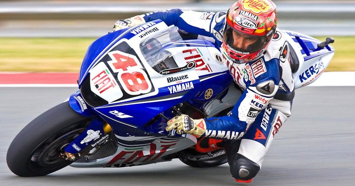 A Yamaha sports bike speeds through a race track, showcasing motorsport excitement.