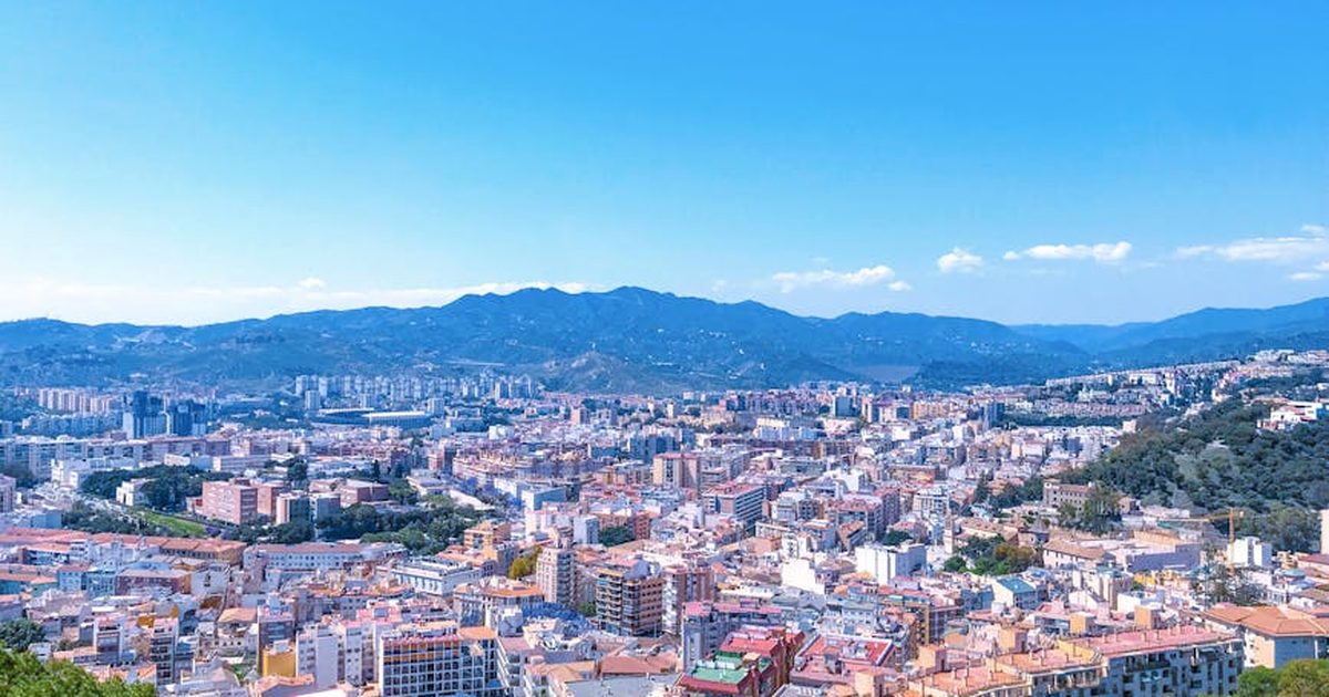 Experience a stunning aerial view of Malaga, Spain with clear blue skies and urban landscape.
