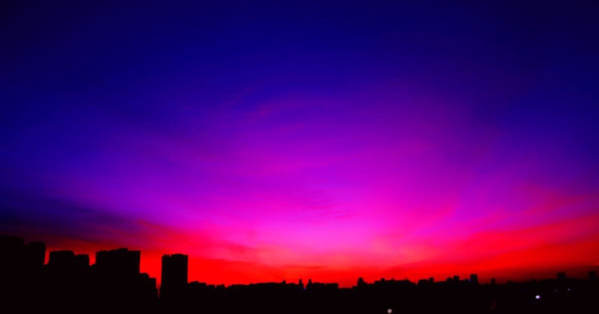 A colorful sunset paints the sky over an urban skyline, creating a dramatic silhouette.