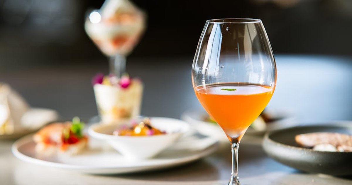 A beautifully set table featuring an orange beverage and assorted gourmet desserts in a refined setting.
