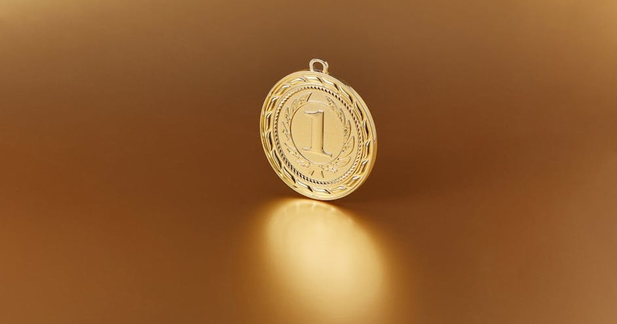 Close-up image of a golden number one medal on a soft golden background.