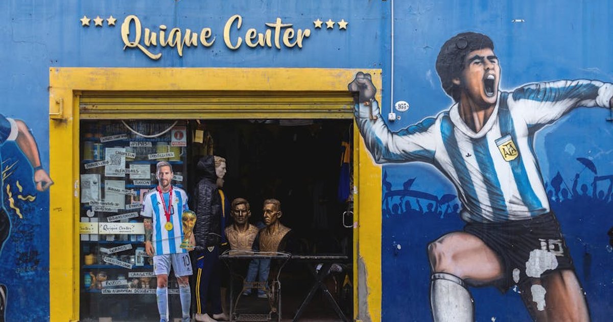 Vibrant storefront in La Boca featuring murals of football legends Maradona and Messi.