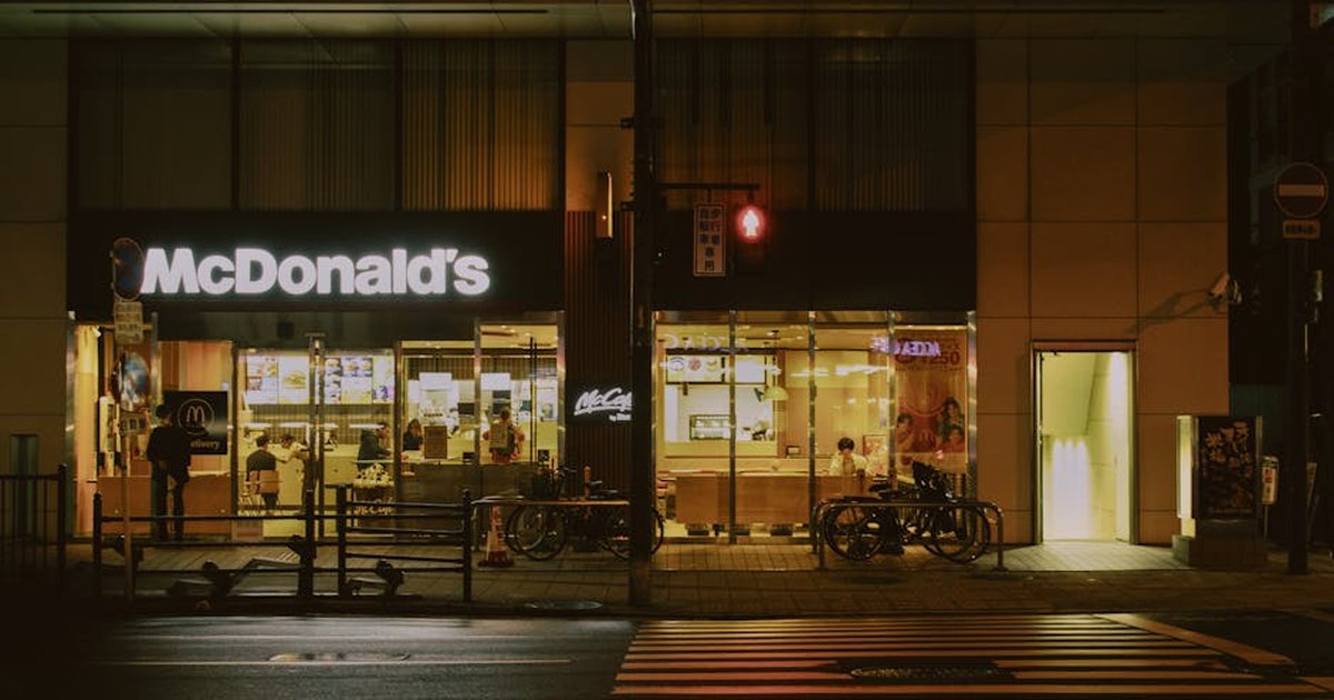 Night view of a McDonald's with traffic light and bicycles, urban setting.