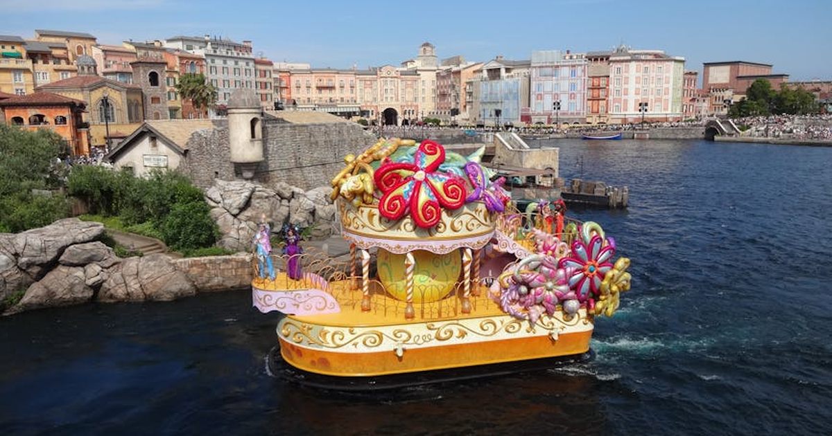 Vibrant parade float in the water with backdrop at Tokyo DisneySea theme park.