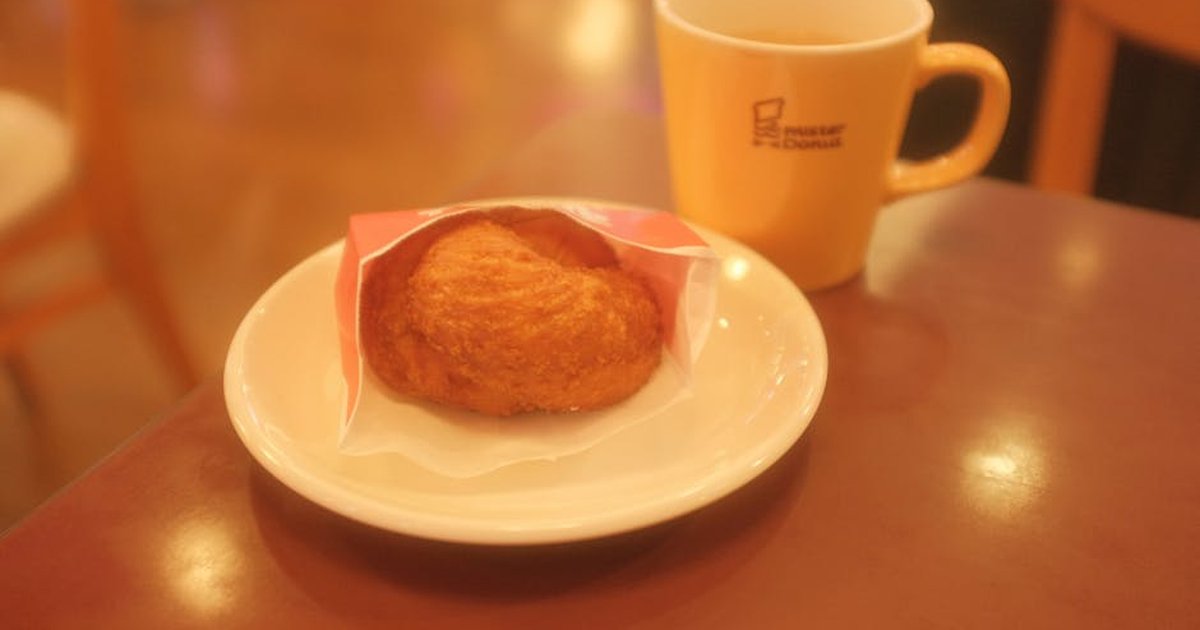 Warm cafe setting featuring a pastry on a plate and a steaming mug of coffee.