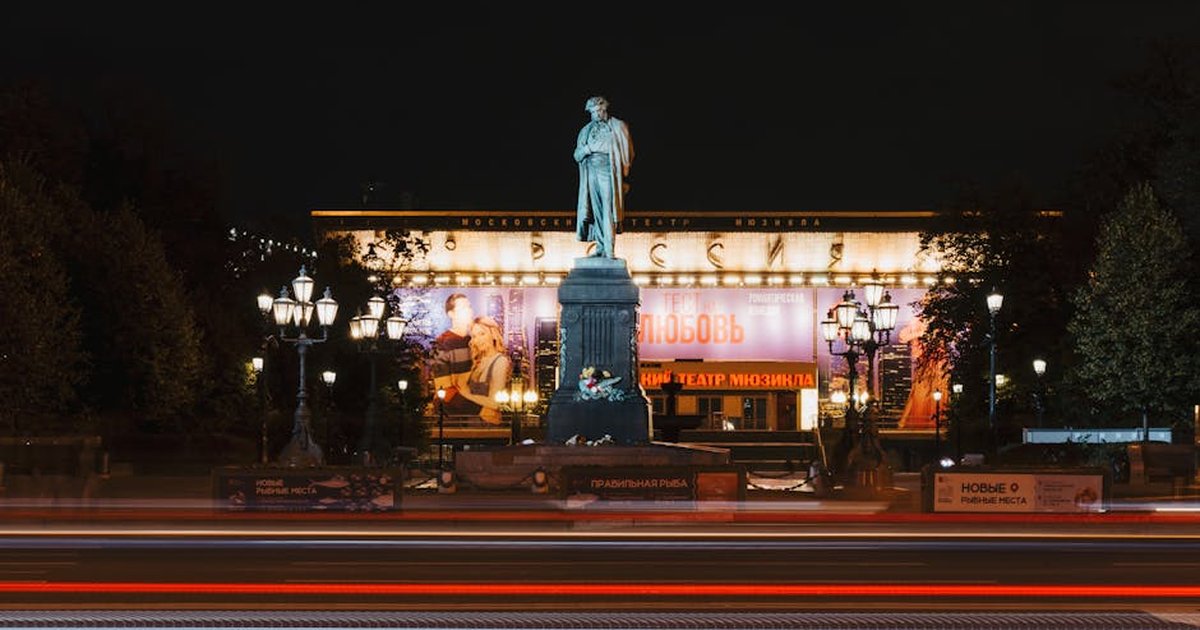 Illuminated monument and theater with streaking lights in Moscow at night.