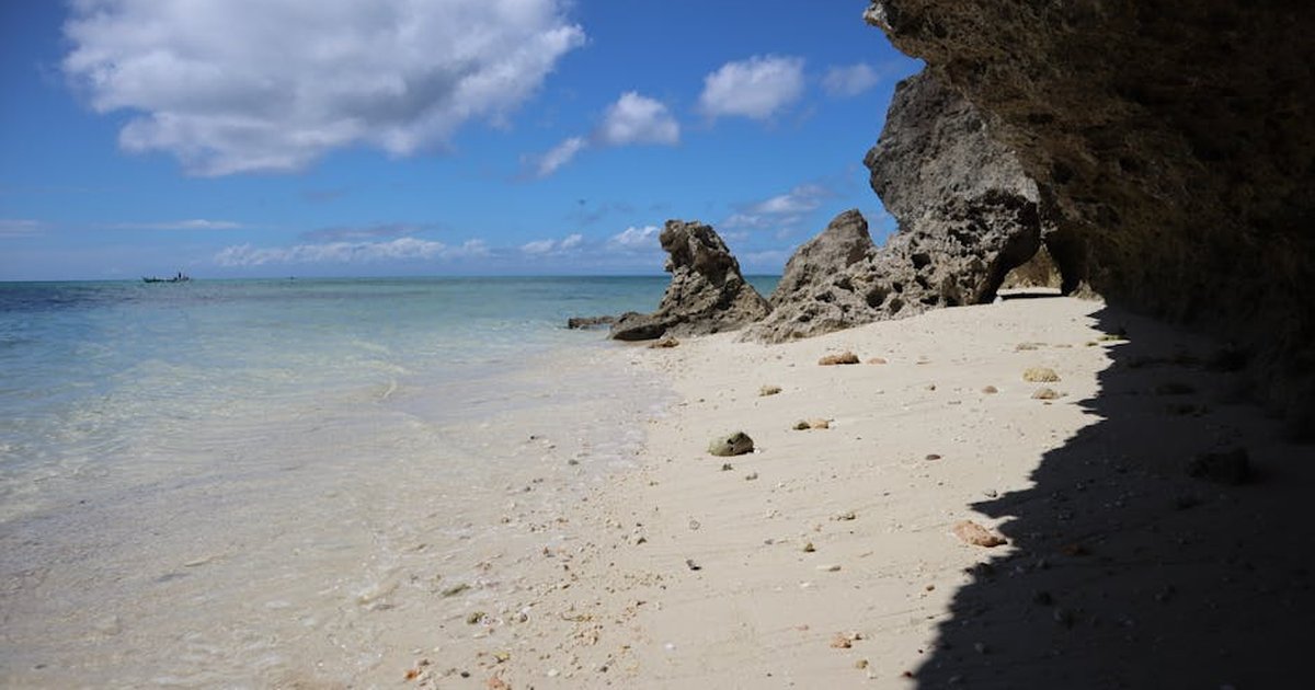 A picturesque beach with rocky cliffs and clear blue sky. Ideal for nature lovers.