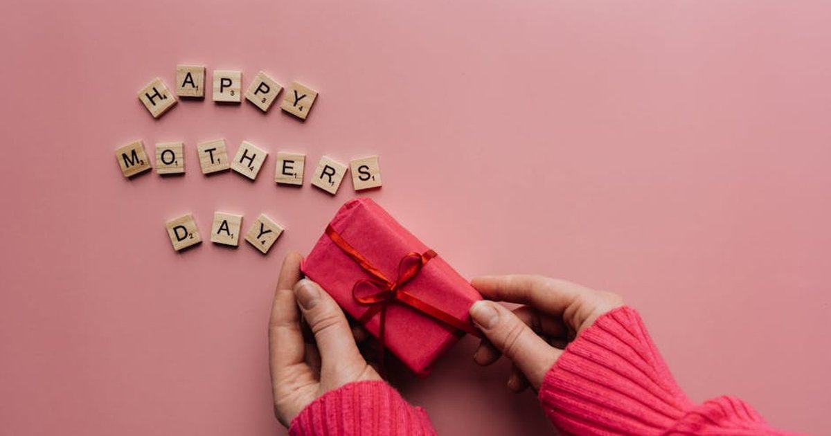 A heartfelt Mother's Day greeting with a gift on a pink background.