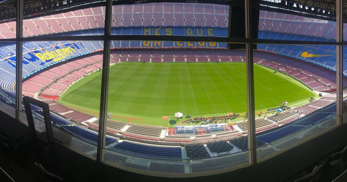 Wide view of Camp Nou stadium showcasing its vast seating and green pitch.